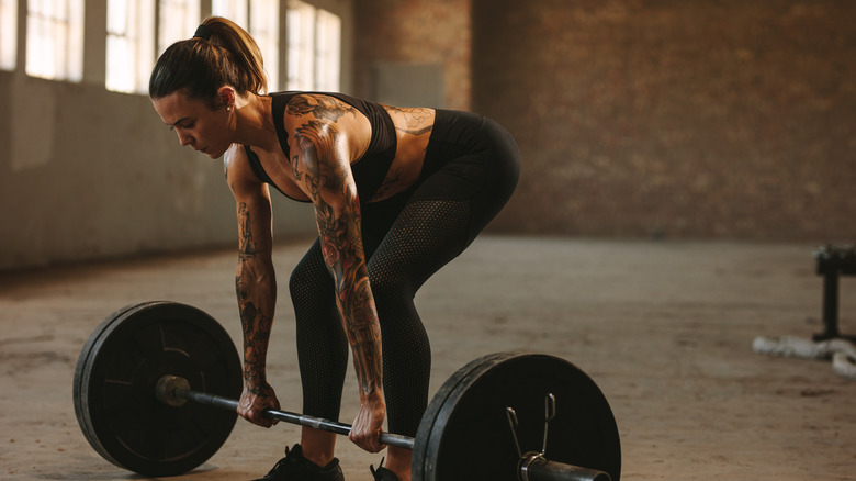 tattooed woman beginning to deadlift