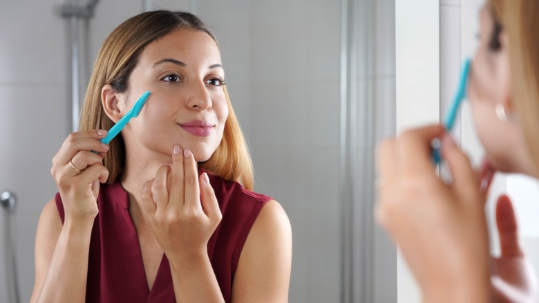 Woman shaving her face