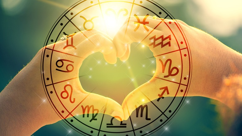 Hands making heart with astrology symbols