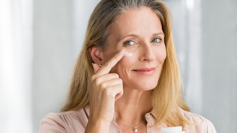 Woman applying lotion to face