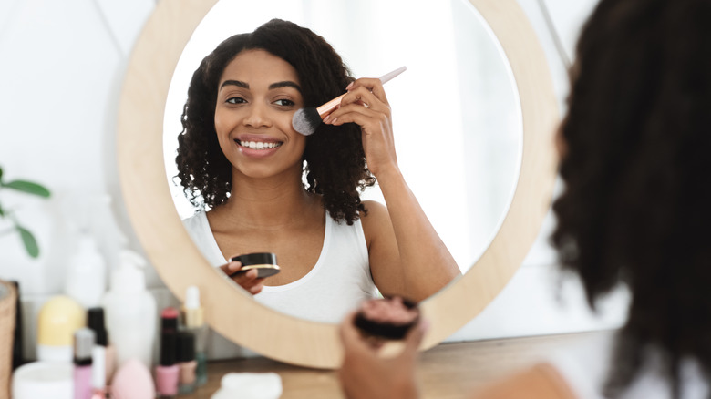 happy woman applying makeup