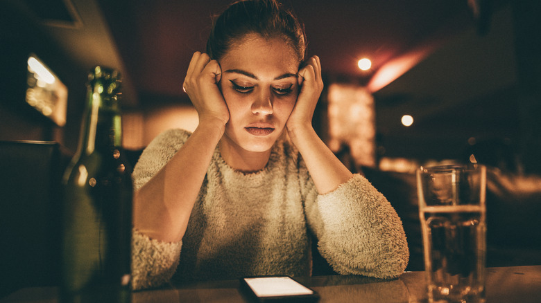 Woman waits for text message at bar