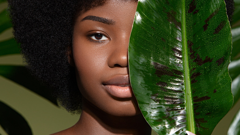 Woman holding leaf to her face