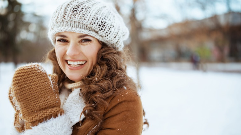Woman poses wearing mitten in snow