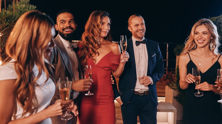 guests raise glasses of champagne at outdoor formal party