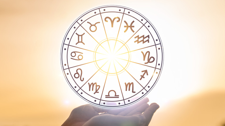 hands cupping zodiac wheel
