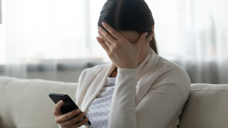 woman holding face and phone