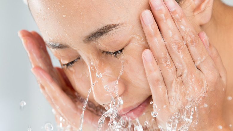 Woman washing face with water 