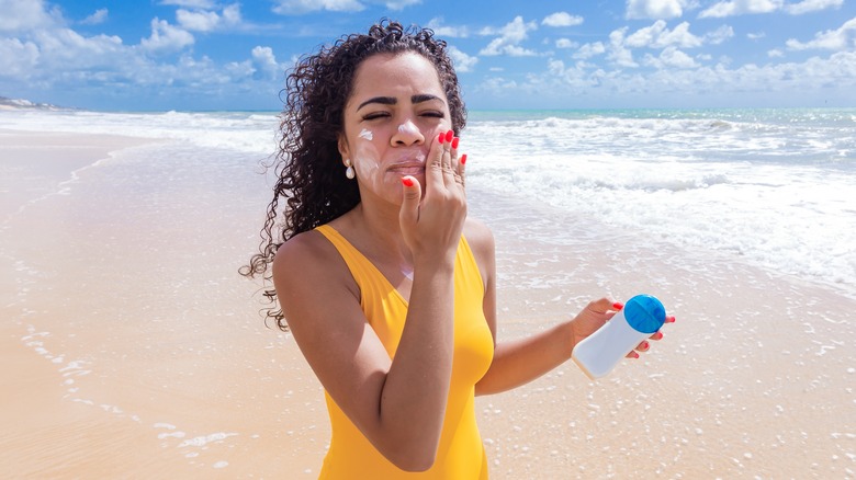 Woman on beach applying sunscreen
