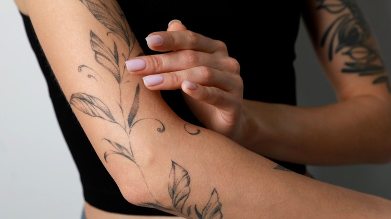 Woman's hand touching arm tattoo