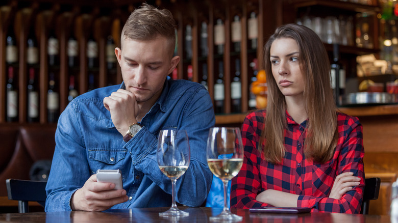 Woman looking at man on phone