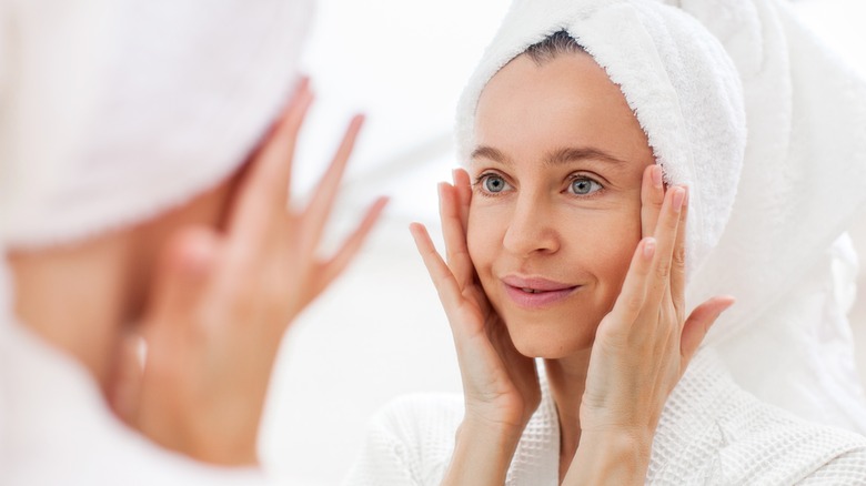 Woman touching face looking in mirror