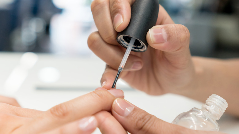 person painting nails with hardener