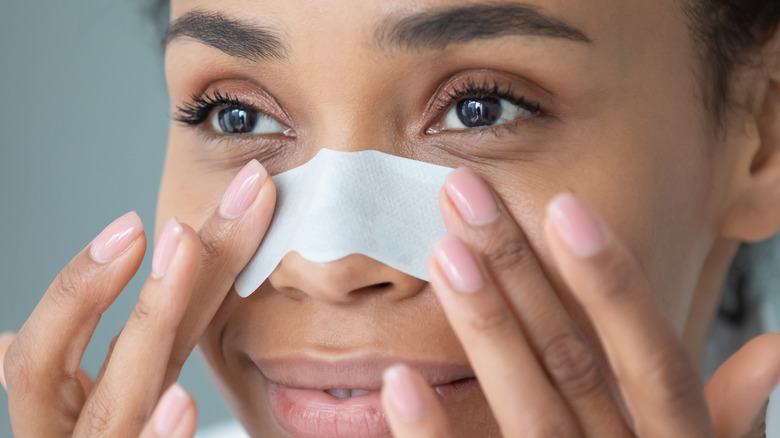 woman putting pore strip on nose 