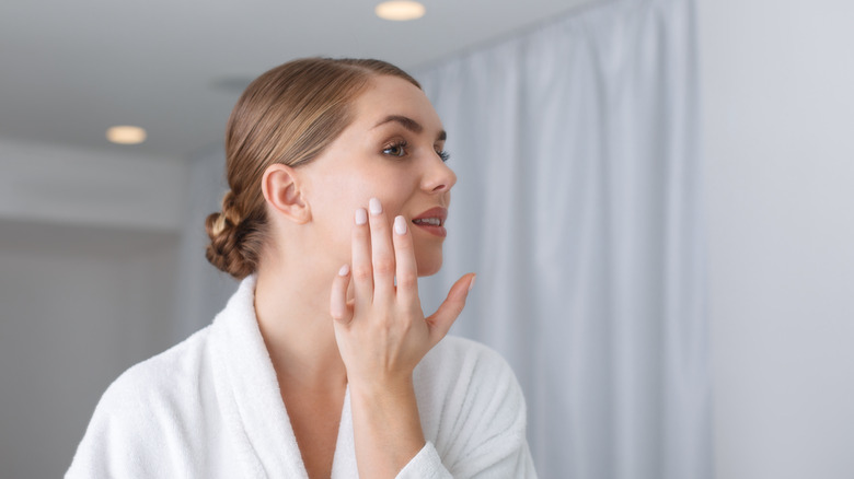 woman observing skin in mirror