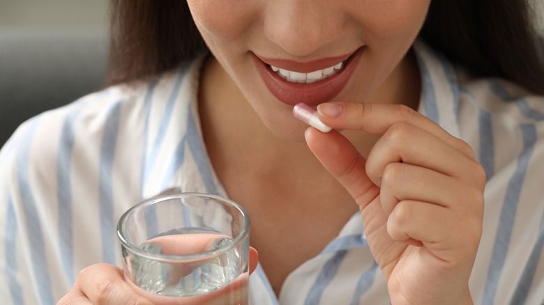 smiling woman taking herbal supplement