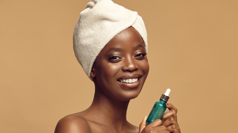 smiling woman holding skincare serum