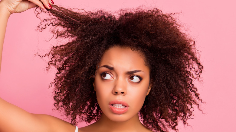 curly-haired woman pulling damaged hair