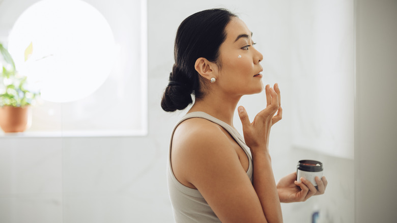 Woman applying cream to face