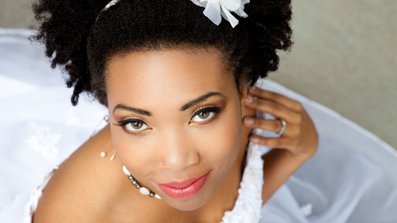 Bride in white headband smiling upward