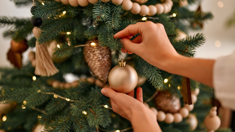 Person hanging ornament on Christmas tree