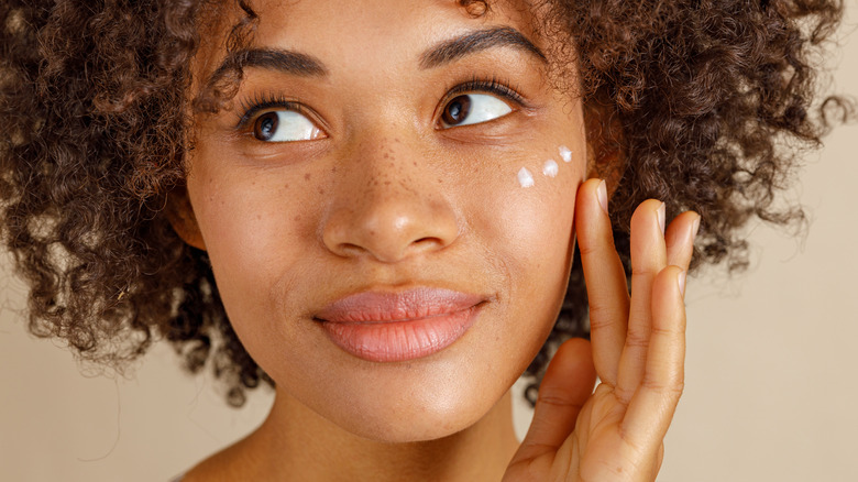 woman rubbing skincare on face