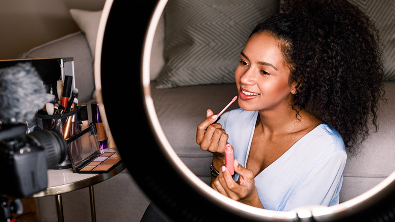 Woman filming beauty tutorial with ring light