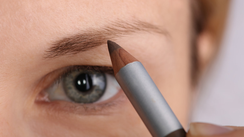 woman using eyebrow pencil 