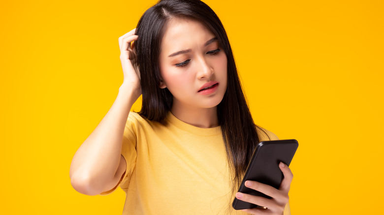 woman scratching head at phone