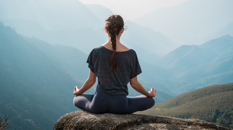 Woman meditating on rock