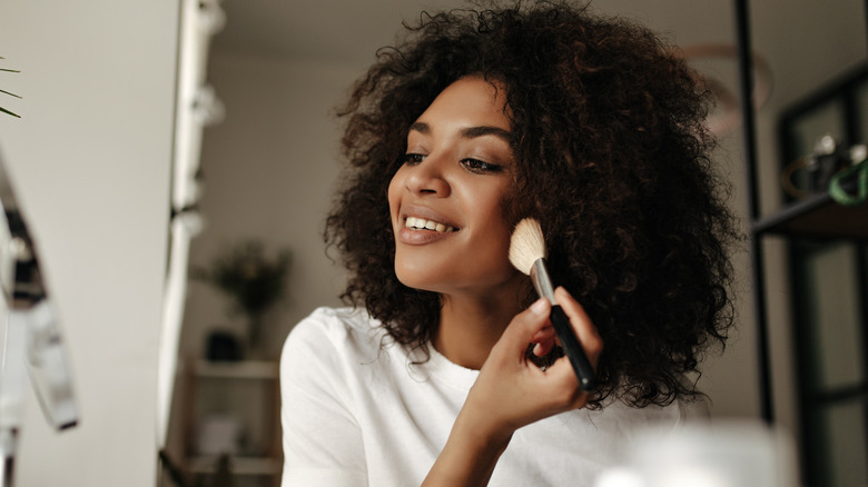 Woman applies makeup to face