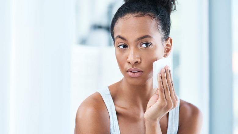 woman using makeup wipe in mirror