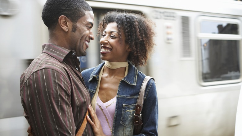 Couple standing by moving train