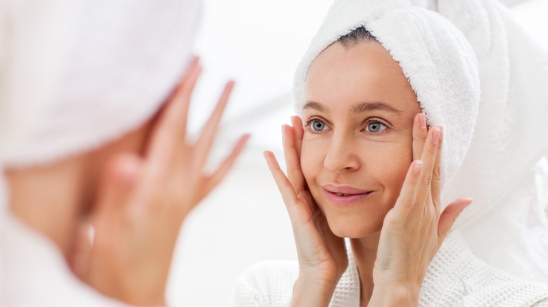 woman looking at skin in mirror