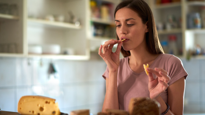 woman eating cheese in kitchen