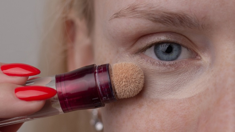 woman applying concealer under eyes