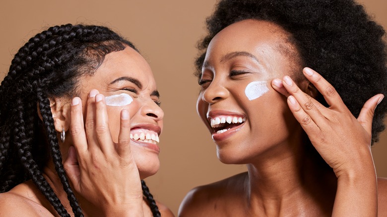 two women applying sunscreen
