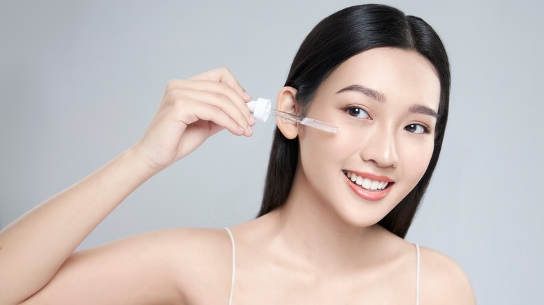 Smiling girl applying serum