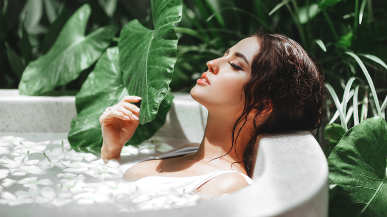 woman taking bath outside surrounded by green plants