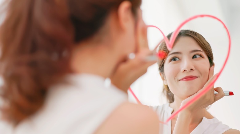 Girl looking at herself in the mirror with red lipstick
