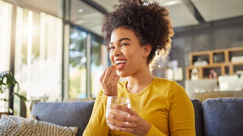 smiling woman consuming vitamin