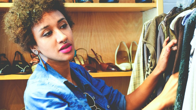 Woman browsing thrift store clothing rack