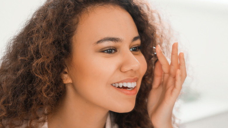 smiling woman inserting contact lens