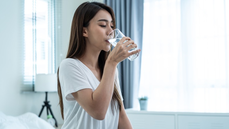 woman drinking water in bed