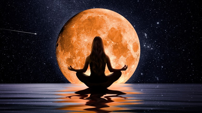 woman meditating under full moon