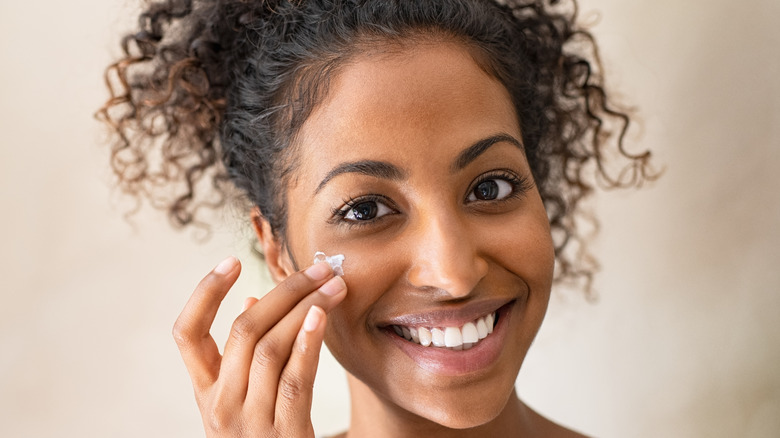 curly haired woman applying cream