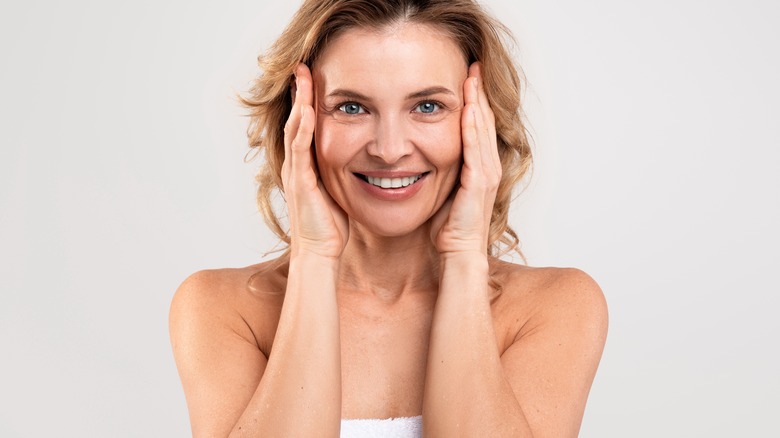 woman wrapped in a towel, touching her face