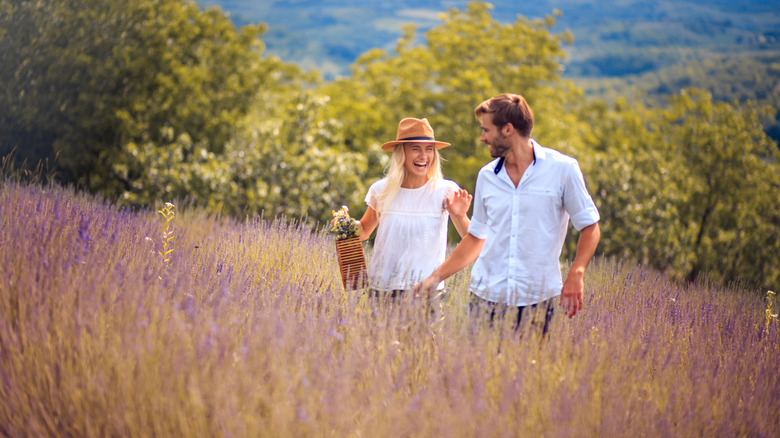 A man and woman walk through a lavender field