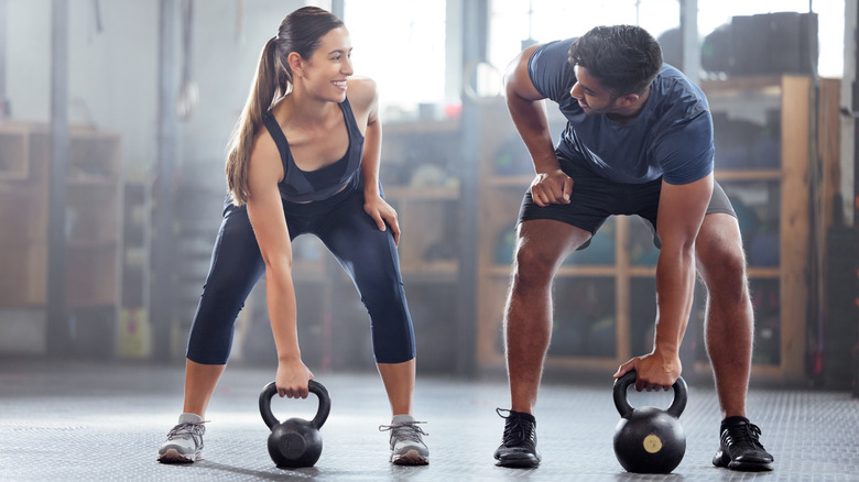 Man and woman lifting kettlebells 