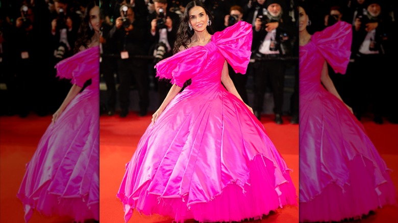 Demi Moore posing for a photo in a tacky-looking hot pink dress with a large bow by Matières Fécales at the 2026 Cannes Film Festival